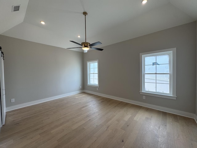 empty room featuring ceiling fan, visible vents, light wood-style flooring, and lofted ceiling