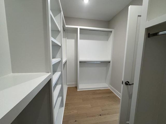 walk in closet with wood finished floors