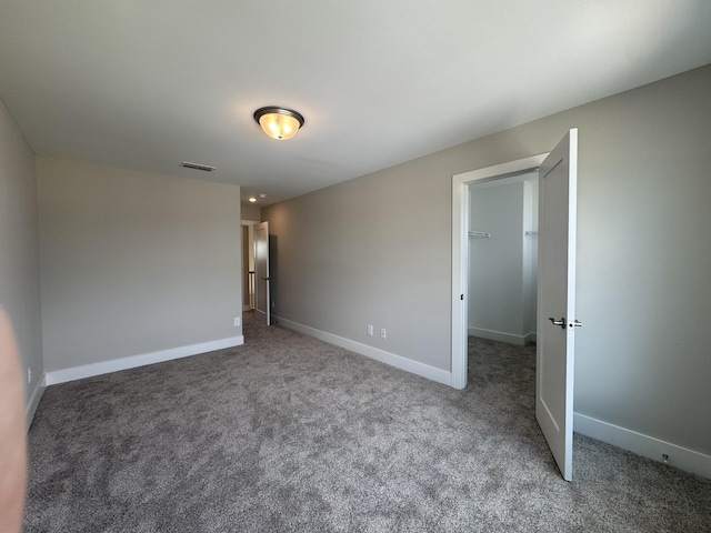 unfurnished bedroom with visible vents, carpet, baseboards, and a spacious closet