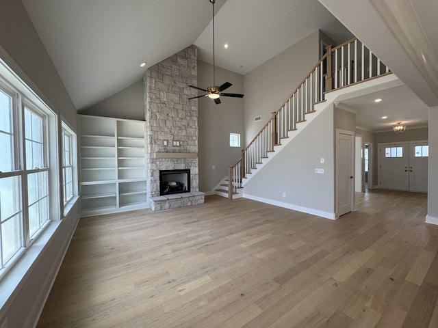 unfurnished living room featuring light wood-style floors, stairs, and a stone fireplace