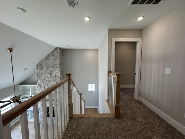 hallway with carpet floors, visible vents, baseboards, and an upstairs landing