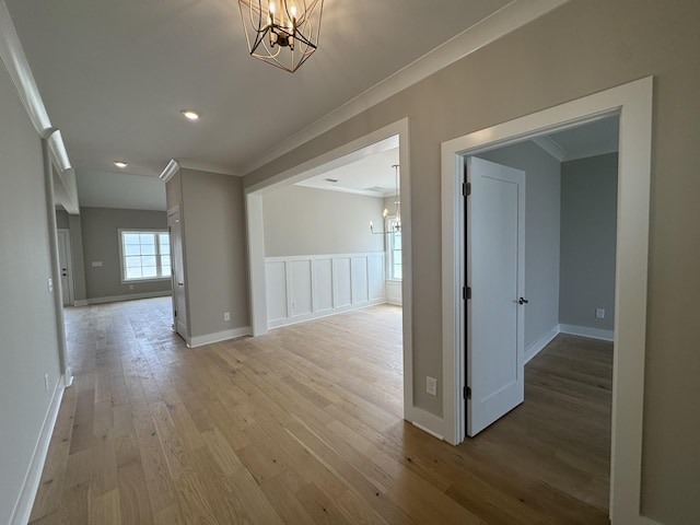 hall with crown molding, baseboards, a chandelier, and light wood-type flooring