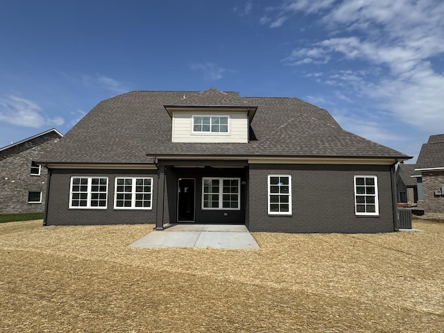 back of house featuring roof with shingles, a patio area, and brick siding