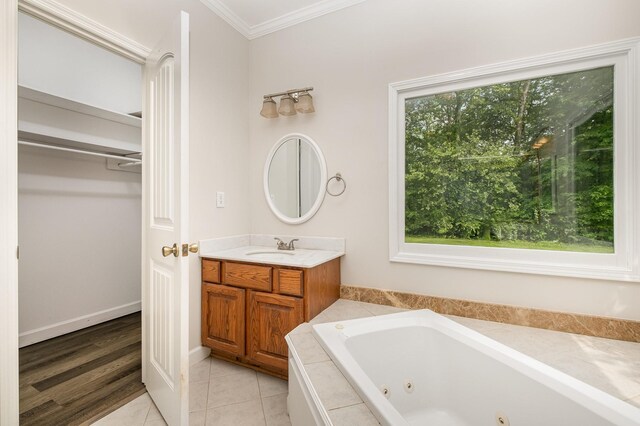 bathroom featuring tile patterned flooring, a tub with jets, vanity, a spacious closet, and ornamental molding
