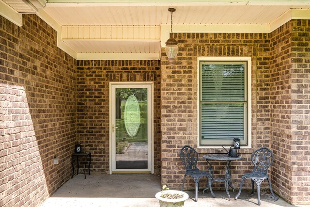 property entrance featuring brick siding and a patio