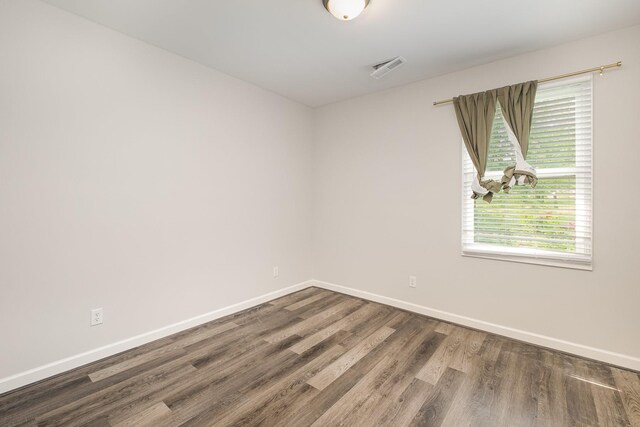 spare room with baseboards and wood finished floors