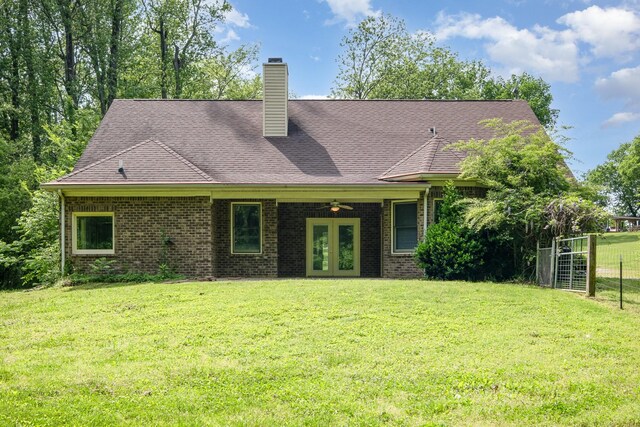 back of house featuring fence, brick siding, a chimney, french doors, and a yard