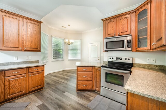 kitchen with wood finished floors, glass insert cabinets, brown cabinets, a chandelier, and appliances with stainless steel finishes