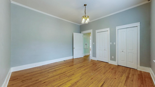 706 N Church St, Murfreesboro, TN 37130 - unfurnished bedroom with crown molding, two closets, baseboards, light wood finished floors, and a notable chandelier