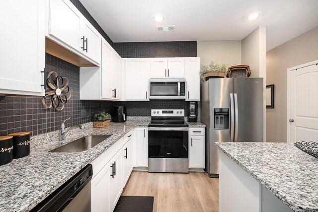 156 Cecil Rd, Lebanon, TN 37087 - kitchen with stainless steel appliances, a sink, white cabinets, light wood-style floors, and tasteful backsplash