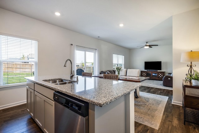 kitchen featuring ceiling fan, light stone countertops, dishwasher, a sink, and baseboards