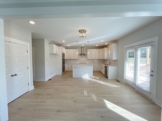 kitchen featuring wall chimney range hood, a sink, dishwasher, backsplash, and a kitchen island