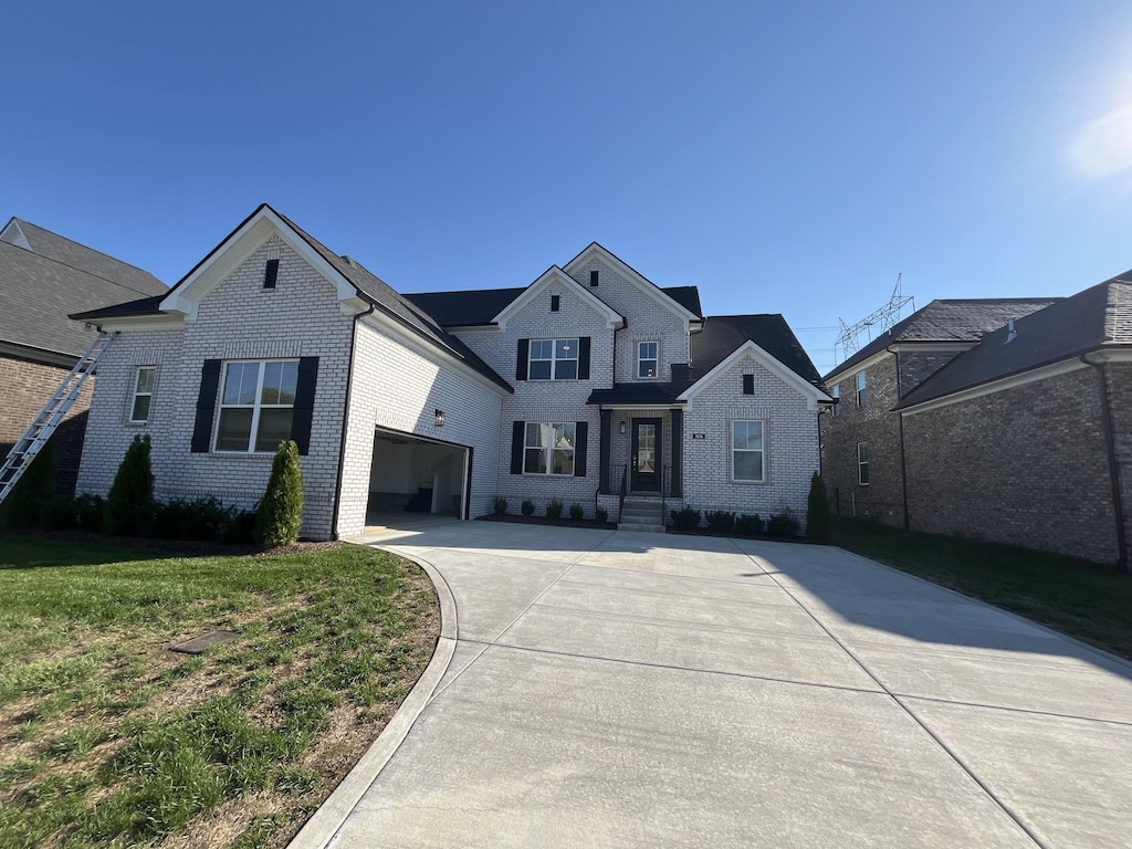 traditional-style house featuring brick siding, a garage, a front lawn, and driveway