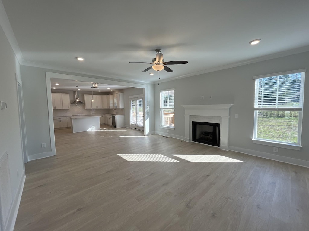 unfurnished living room with crown molding, recessed lighting, baseboards, and a fireplace