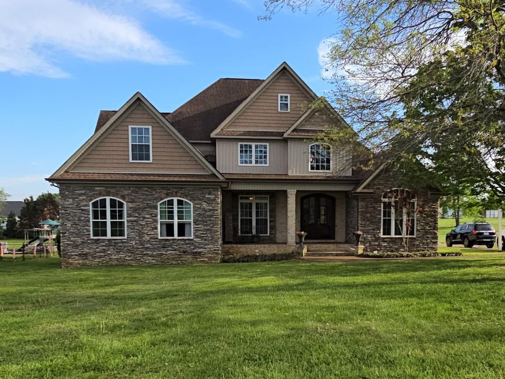 view of front of house featuring a porch, a front lawn, and stone siding