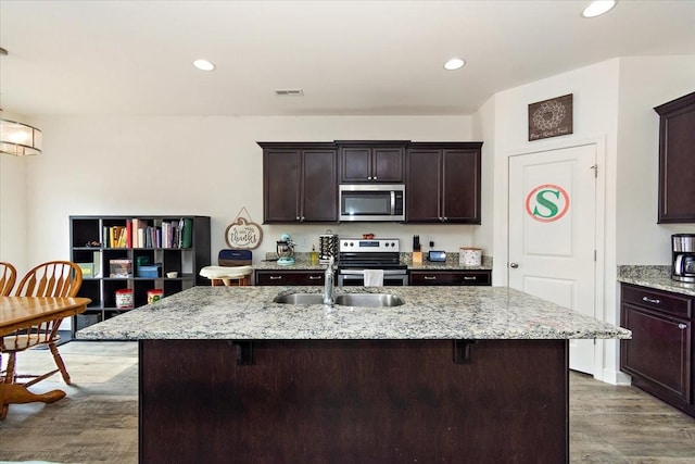 kitchen featuring light stone counters, a sink, stainless steel appliances, recessed lighting, and visible vents