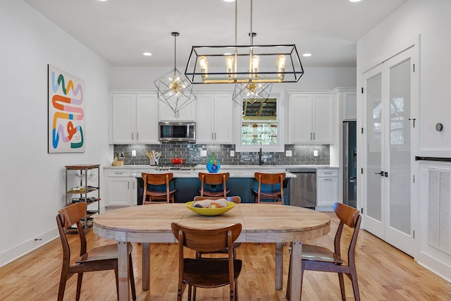 1811 Meridian St, Nashville, TN 37207 - kitchen with light countertops, white cabinetry, tasteful backsplash, light wood-style flooring, and stainless steel appliances