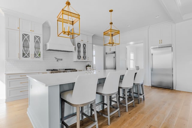 kitchen with light countertops, stainless steel appliances, decorative backsplash, and light wood-type flooring