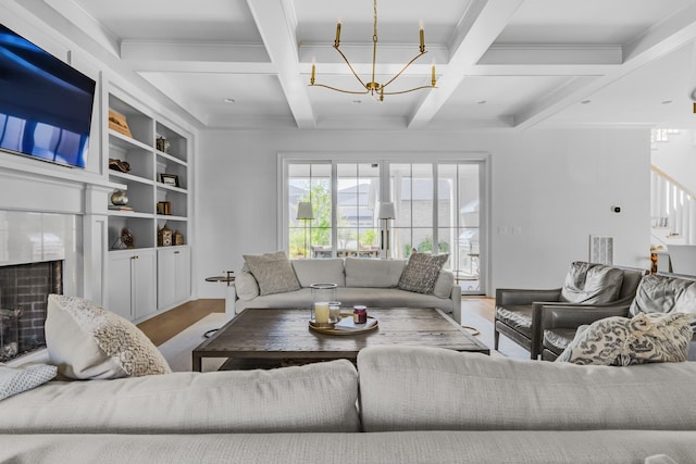 living area featuring a high end fireplace, coffered ceiling, wood finished floors, and a chandelier
