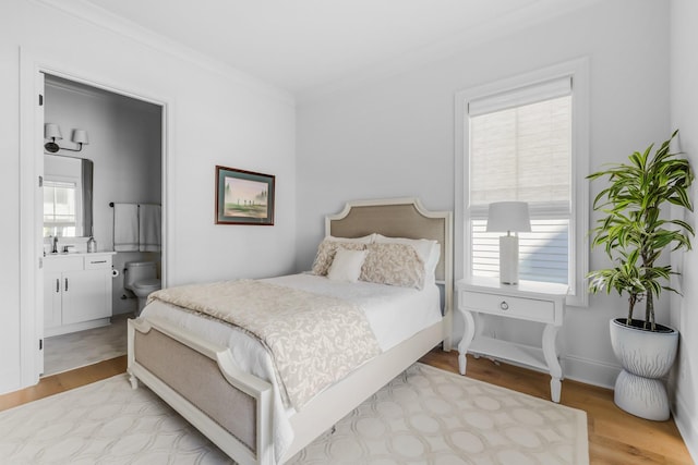 bedroom featuring crown molding, ensuite bathroom, and light wood finished floors