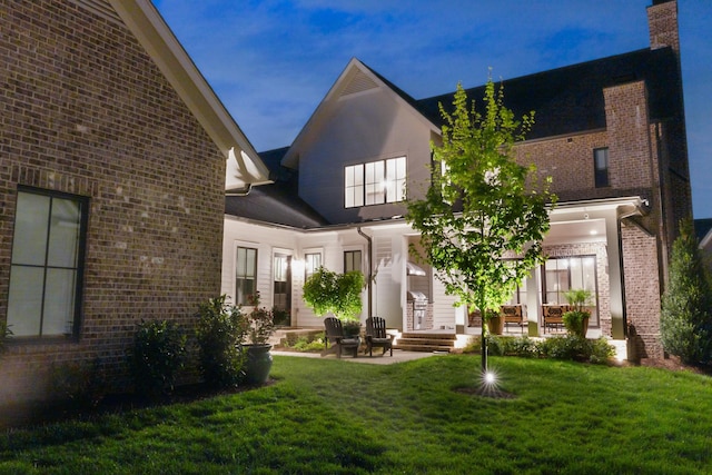 back of house featuring a patio, a yard, and brick siding