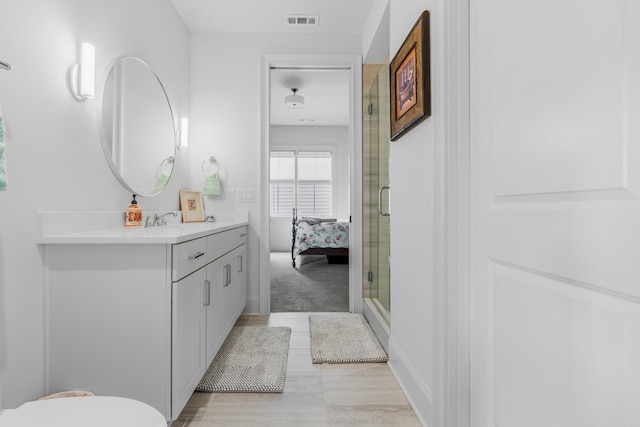 bathroom featuring connected bathroom, vanity, baseboards, a shower stall, and visible vents