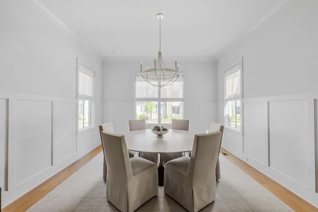 dining room featuring light wood-style floors, plenty of natural light, a decorative wall, and a notable chandelier