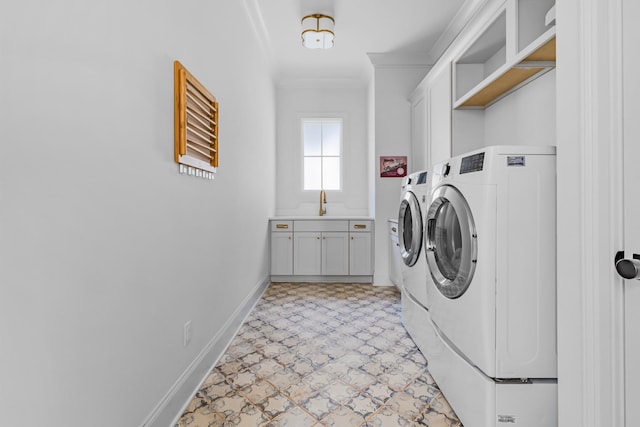 laundry area featuring cabinet space, a sink, ornamental molding, baseboards, and washing machine and dryer