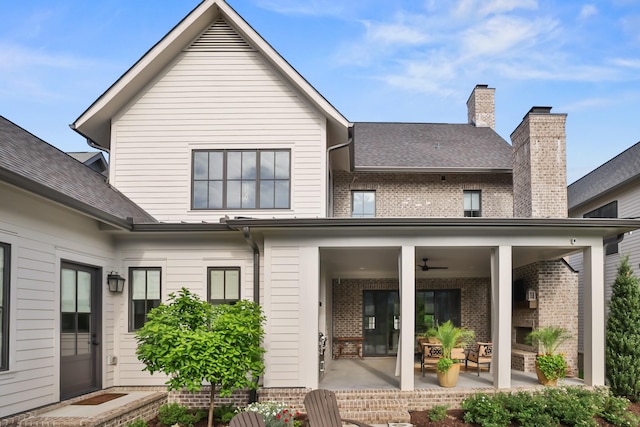 back of house with a ceiling fan, a chimney, a patio area, brick siding, and a shingled roof