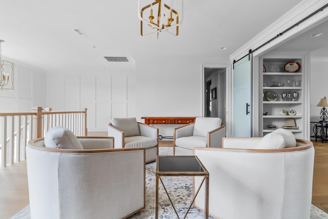 living room with visible vents, a barn door, wood finished floors, and a chandelier