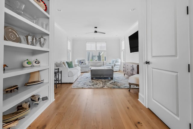 living room with ceiling fan, built in features, and light wood-type flooring