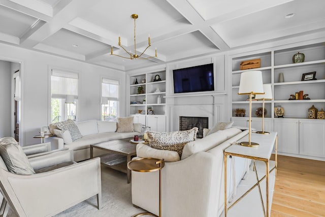 living room featuring a high end fireplace, an inviting chandelier, coffered ceiling, and light wood finished floors