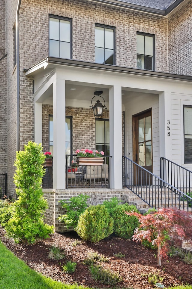 doorway to property with covered porch and brick siding