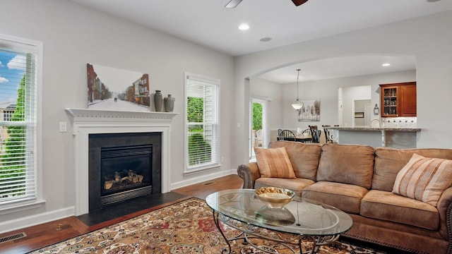 1011 Gatewick Ct, Franklin, TN 37067 - living area featuring wood finished floors, arched walkways, baseboards, a ceiling fan, and a fireplace with flush hearth