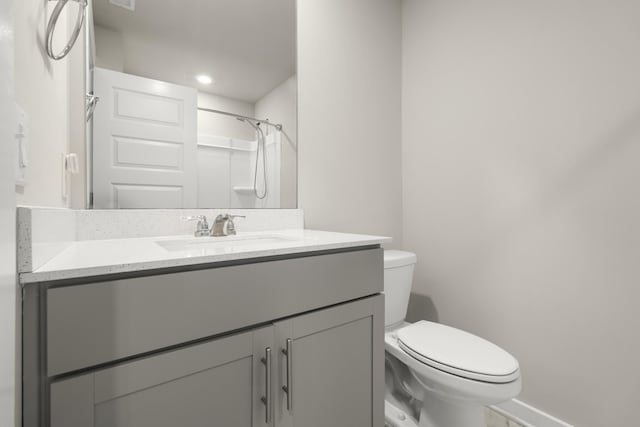 full bath with vanity, baseboards, walk in shower, and toilet