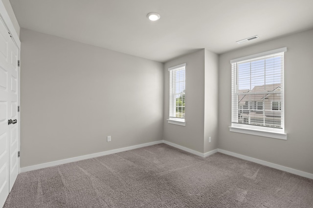 spare room featuring baseboards, carpet floors, and visible vents