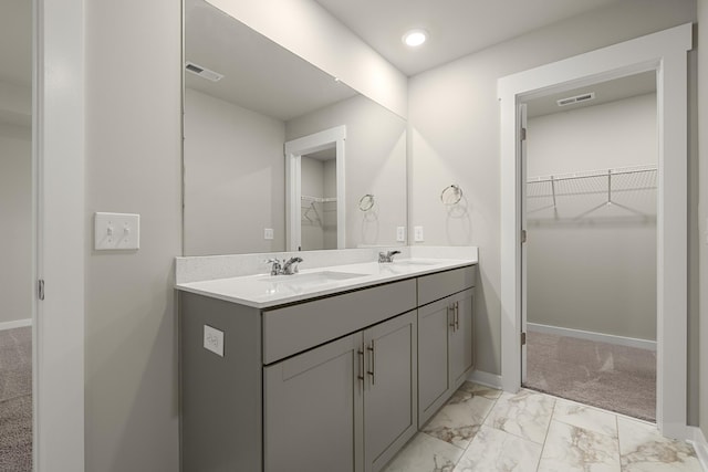 full bath featuring double vanity, a sink, marble finish floor, and a walk in closet