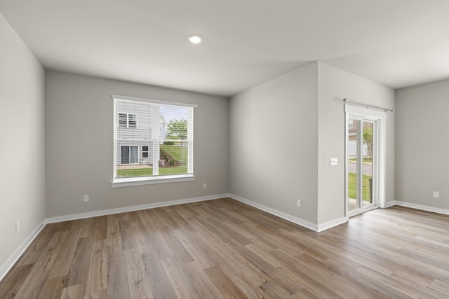 empty room featuring recessed lighting, baseboards, and light wood-type flooring