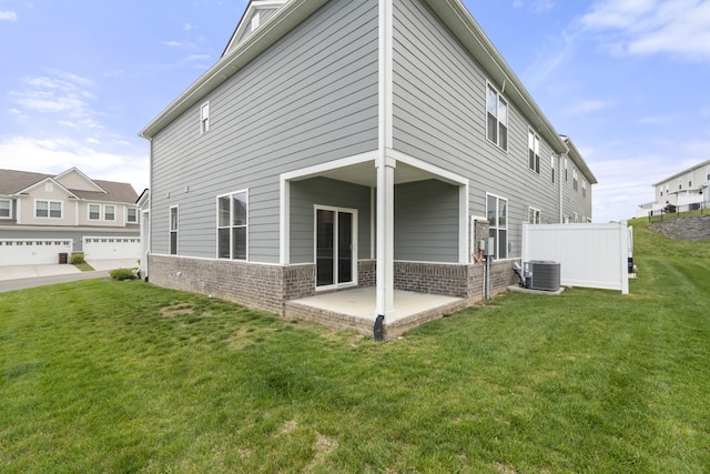 back of property with fence, brick siding, a patio area, central air condition unit, and a yard