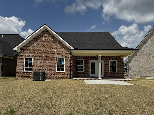 rear view of property featuring brick siding and central AC