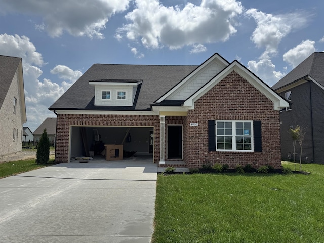 view of front facade with brick siding, a front lawn, roof with shingles, and driveway
