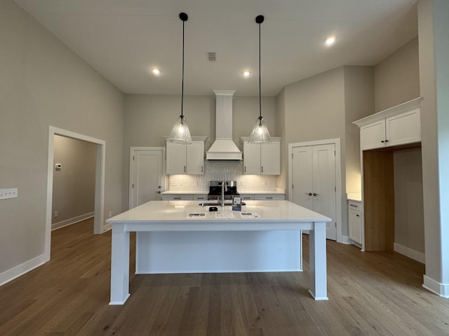 4020 Runyan Cv, Murfreesboro, TN 37127 - kitchen with custom range hood, tasteful backsplash, white cabinets, a center island with sink, and wood finished floors