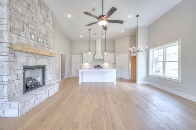 4020 Runyan Cv, Murfreesboro, TN 37127 - living room featuring a high ceiling, a chandelier, a stone fireplace, ceiling fan, and light wood-style floors