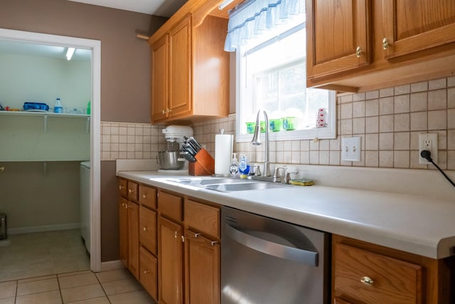 kitchen with a sink, dishwasher, light countertops, brown cabinetry, and light tile patterned floors