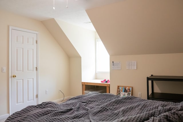bedroom with baseboards and lofted ceiling