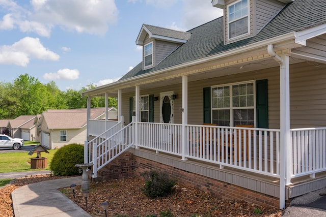 property entrance with roof with shingles and a porch