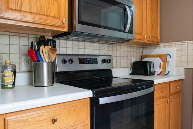 kitchen with backsplash, stainless steel appliances, brown cabinets, and light countertops