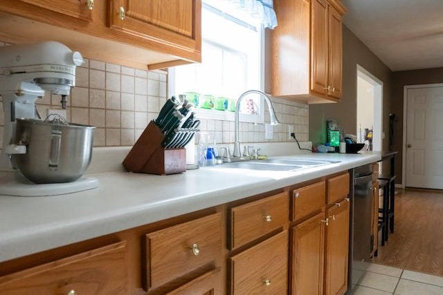 kitchen with brown cabinetry, a sink, decorative backsplash, and light countertops