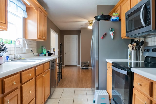 kitchen featuring ceiling fan, light countertops, tasteful backsplash, a sink, and appliances with stainless steel finishes
