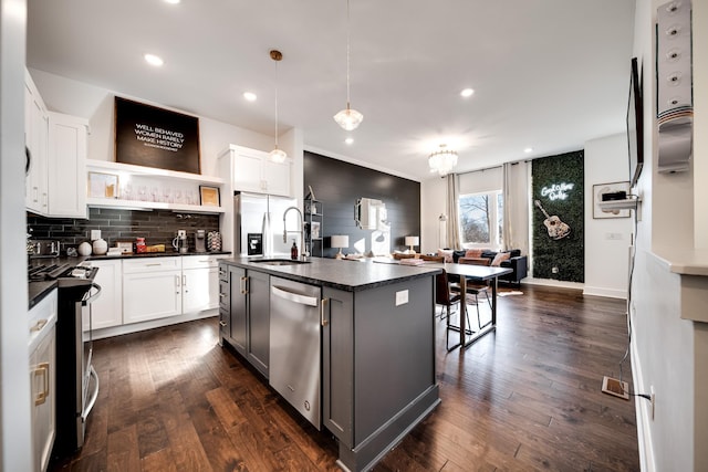 kitchen with dark countertops, open shelves, a sink, stainless steel appliances, and decorative backsplash